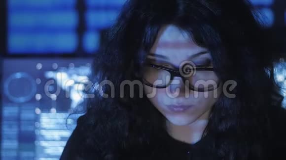 戴眼镜的女性黑客程序员正在电脑安全中心工作里面放满了显示屏二元视频的预览图