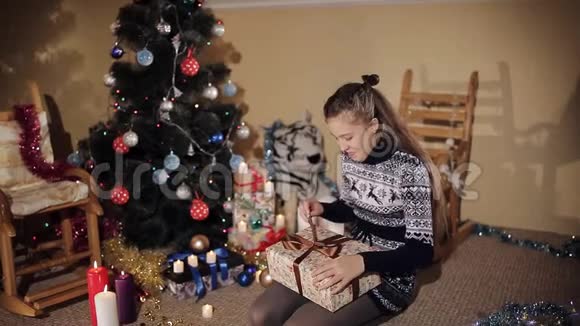 圣诞树旁美丽的少女打开礼物盒里面有圣诞老人送给的新年礼物视频的预览图