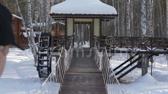 在冬季城市公园后景的装饰桥上行走的成年男子视频的预览图