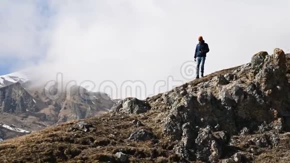 戴着帽子太阳镜脖子上戴着相机的胡子男摄影师爬上了山坡视频的预览图