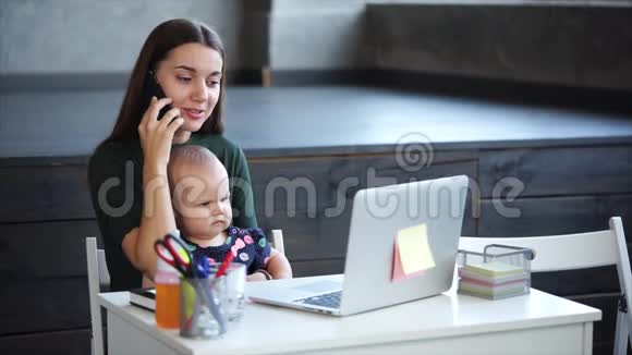 在一项法令中一位商业母亲正在用智能手机说话并抱着一个女儿视频的预览图