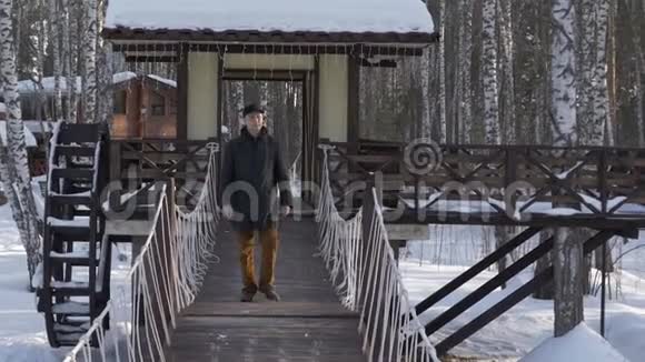在冬季城市公园的装饰桥上行走的帅哥视频的预览图