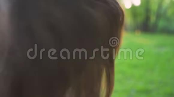 年轻迷人的女孩在公园的特写镜头里旋转头发视频的预览图