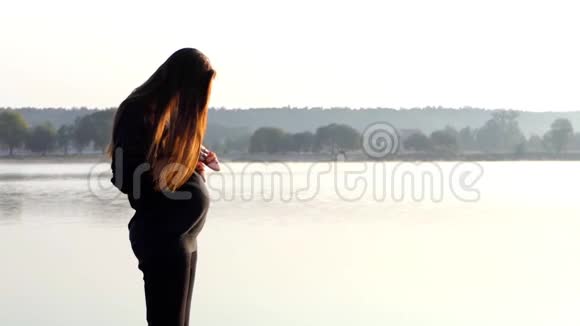 一个漂亮的孕妇与婴儿的拖鞋在秋天的日落在斯隆莫视频的预览图
