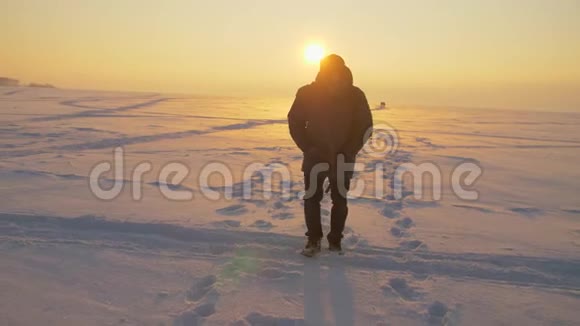 傍晚一个人穿过白雪覆盖的沙漠夕阳照在雪上视频的预览图