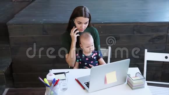 那个女人在智能手机上说话做笔记在办公室抱着一个孩子视频的预览图