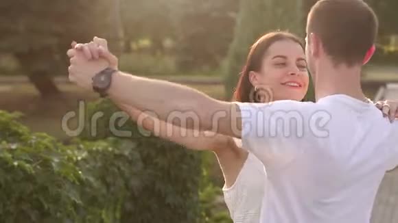 快乐的年轻情侣在公园日落时跳着慢华尔兹视频的预览图