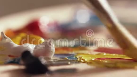 画家用大画笔在调色板上混合不同颜色的油画视频的预览图