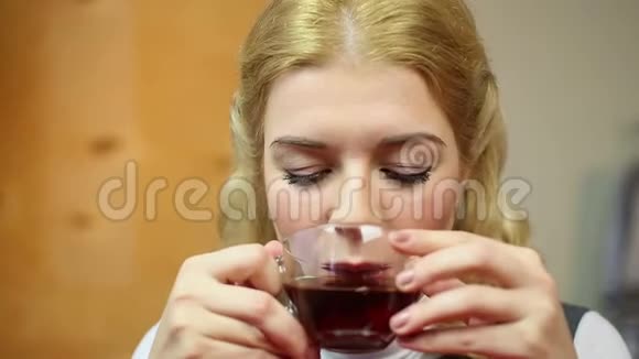 女孩从杯子里喝红茶快乐女性品尝热辣饮料视频的预览图