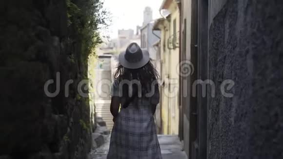 从后面的女孩走在狭窄的街道上视频的预览图