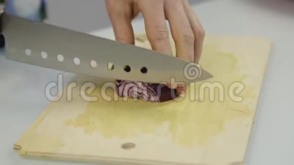 女人的手在厨房里用木板切红洋葱视频的预览图