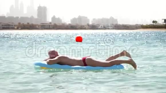 一个男人躺在充气床垫上在海里游泳日光浴在辛苦工作了一周后休息的商人视频的预览图