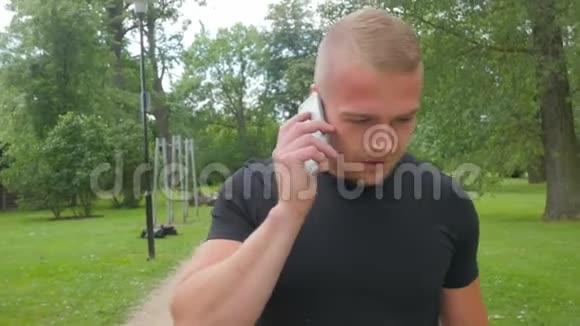 在公园打电话的肌肉发达男子视频的预览图