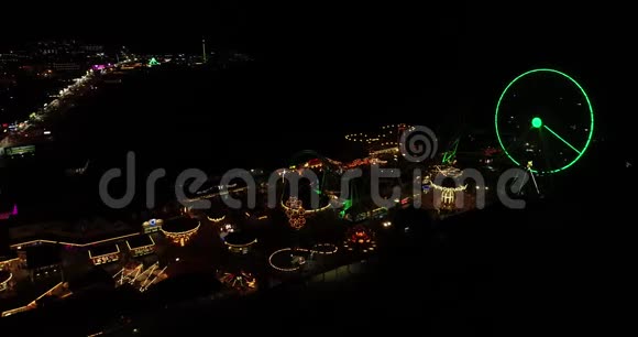 木板路游乐码头夜间无人机拍摄的空中录像灯光明亮天空漆黑视频的预览图