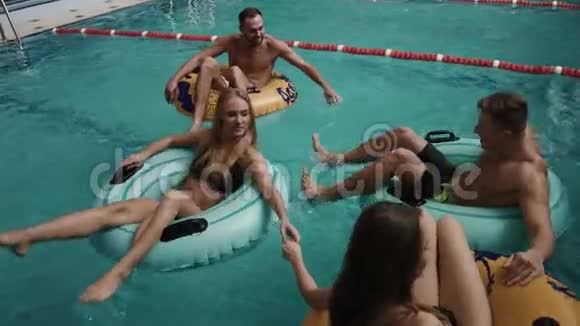 幸福四友在豪华酒店泳池的充气橡胶圈上游泳4k视频的预览图