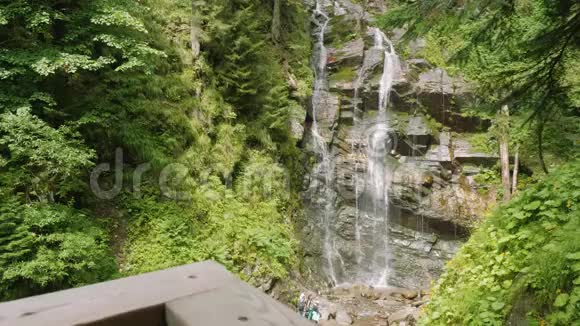 森林中的瀑布景观和游客在下面散步视频的预览图