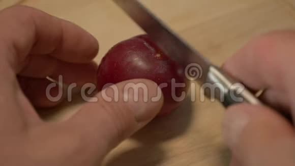一人削一红梅成两片在木制背景上视频的预览图