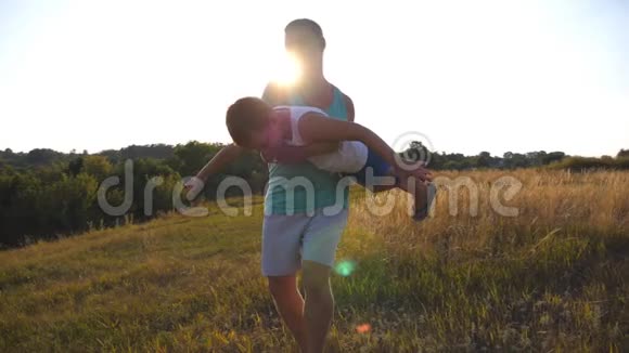 日落时分父亲和儿子在田野上玩耍快乐的爸爸把他的孩子旋转在手里男孩想象他飞得像视频的预览图