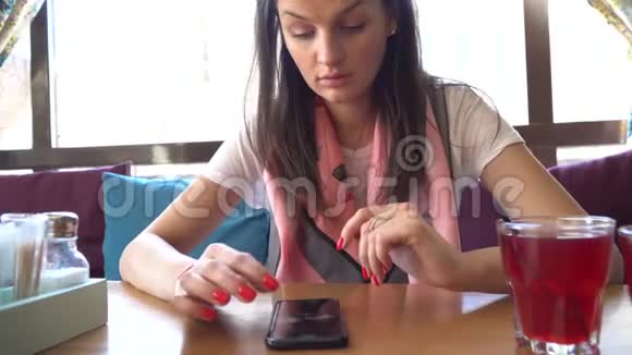 美丽的女人在咖啡馆里使用智能手机视频的预览图