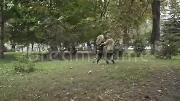 可爱的女孩和可爱的男孩牵着手慢动作在公园里奔跑视频的预览图