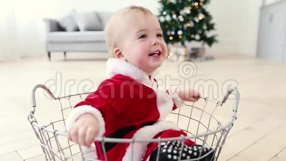 婴儿圣诞老人套装和圣诞树一起坐在篮子里视频的预览图