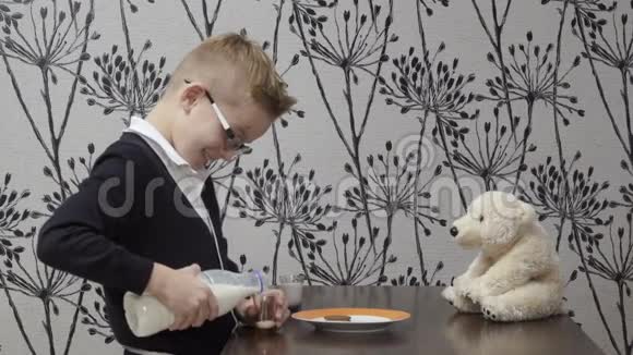 有趣的男孩和他的朋友玩具熊一起喝牛奶视频的预览图