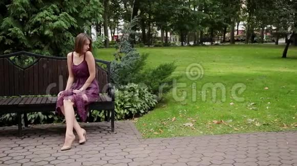 非常漂亮和女孩坐在公园的长凳上视频的预览图