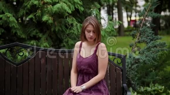 非常漂亮和女孩坐在公园的长凳上视频的预览图