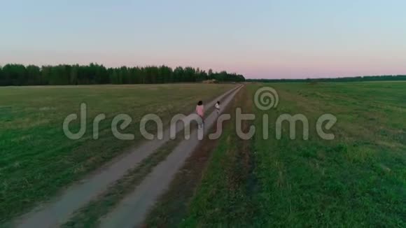 母亲带着女儿在夕阳下的乡村道路上奔跑视频的预览图