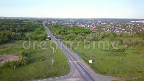 从森林穿过村庄的公路俯视剪辑在村庄背景上与过往车辆的轨迹视频的预览图