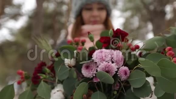 美丽的混血白种人白种人亚洲女孩在冬季雪松林中捧着一束花的肖像视频的预览图