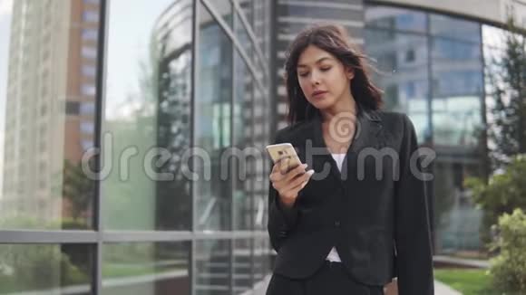 穿商务套装的漂亮女孩使用智能手机年轻商务女性在手机上发短信视频的预览图