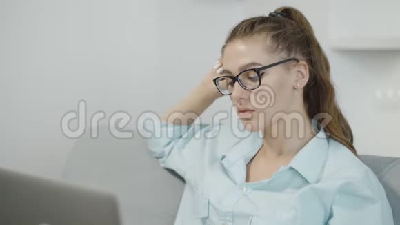 疲惫的少女在家里用笔记本电脑在笔记本上打字准备考试或家庭作业视频的预览图