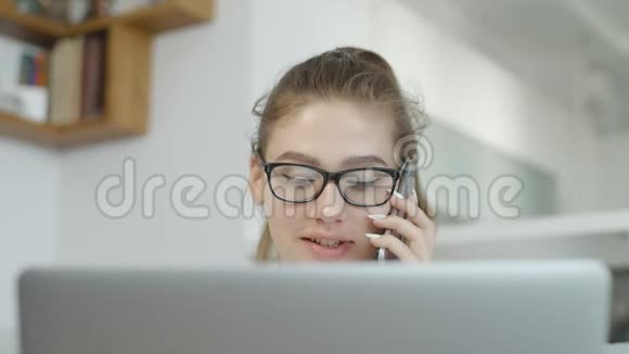 学生女孩说着手机微笑着在家用笔记本电脑在社交网络上聊天视频的预览图