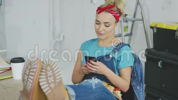 微笑的女人用智能手机坐在工作台上视频的预览图