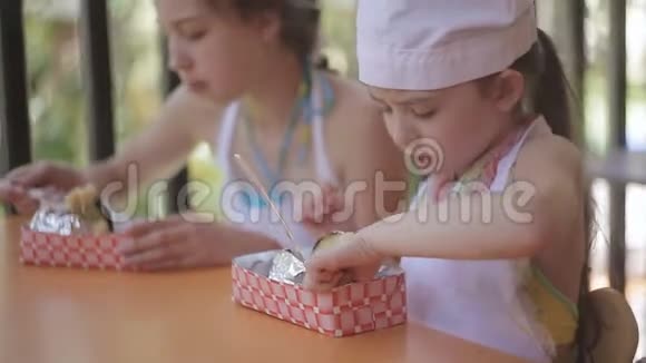 一个儿童营地两个小女孩在餐桌旁吃饭视频的预览图