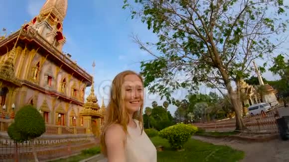 泰国普吉岛一名年轻女子在一座瓦查朗佛教寺庙前自拍的慢镜头视频的预览图