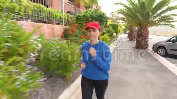 女人沿着街道在热带小巷里慢跑视频的预览图
