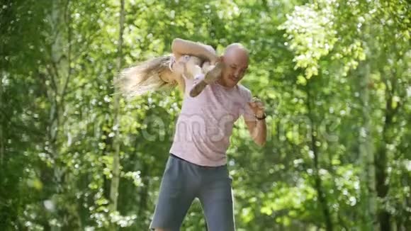 爸爸在公园里和女儿玩正在扔他的小宝宝慢动作视频的预览图