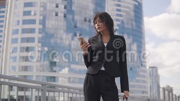 一个穿正式西装的女人的特写肖像年轻商务女性在手机上发短信视频的预览图