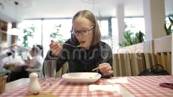 年轻迷人的女孩或女人在城里的咖啡馆里吃沙拉时看着智能手机无法辨认的人视频的预览图
