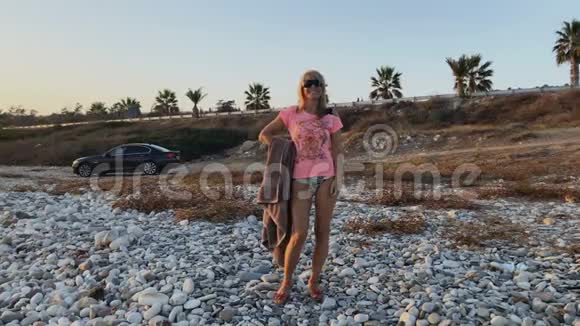 戴墨镜的美女在石滩竖起大拇指视频的预览图