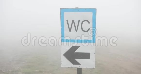 雾天街道指示牌山上覆盖着雾的WC标志的特写视频的预览图