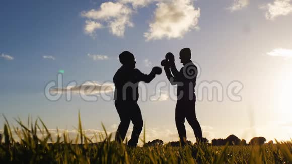 户外拳击训练教练低角度射击对手剪影拳击手套在一个领域的拳击视频的预览图