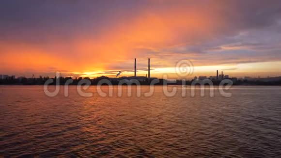 日落背景下从河上的船上俯瞰傍晚的城市大型管道的剪影视频的预览图