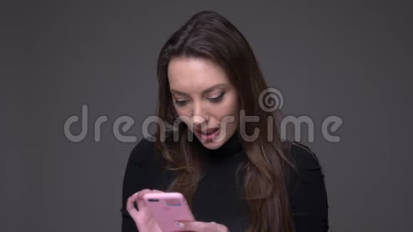 特写照片上的成年白种人迷人的女性在手机上发短信开心地微笑着背景被孤立在视频的预览图