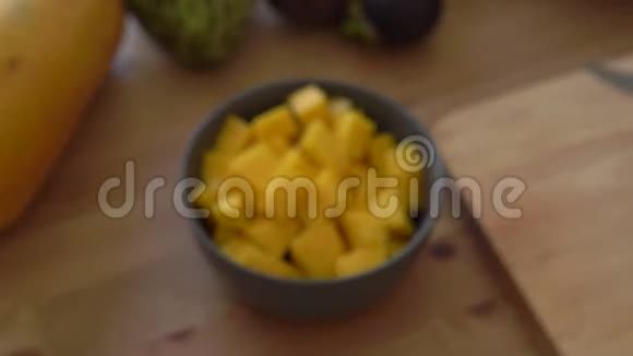 一个灰色陶瓷碗里的芒果立方体和许多热带水果放在桌子上视频的预览图