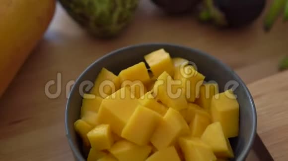 一个灰色陶瓷碗里的芒果立方体和许多热带水果放在桌子上视频的预览图