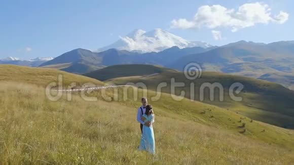 一对时髦的情侣在群山的背景上挽着手视频的预览图