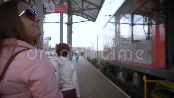 火车站的年轻漂亮的女人去火车带眼镜长发粉色夹克视频的预览图